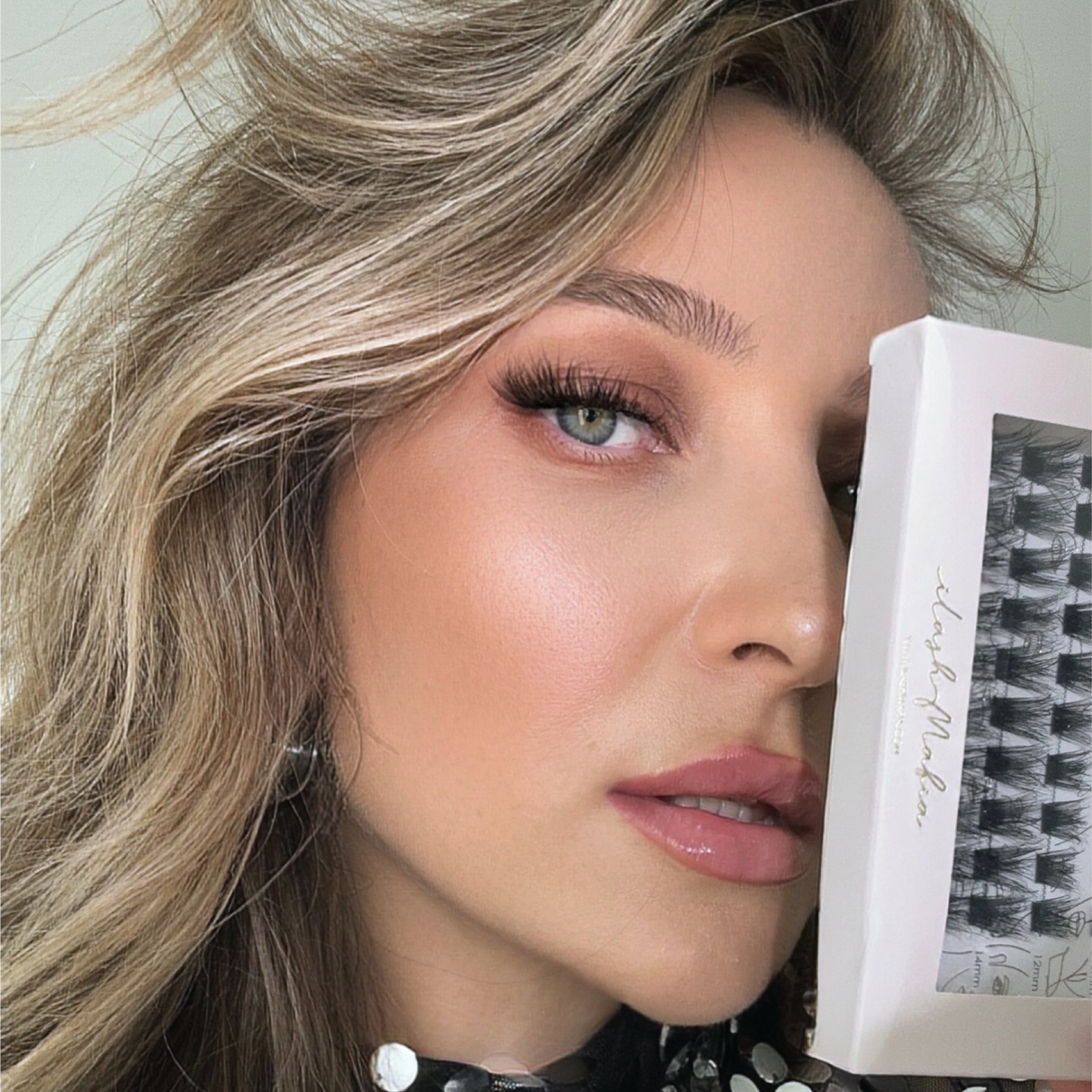 Close-up beauty portrait of a model wearing iLash Mafia Bestie reusable lash clusters while holding the DIY lash extension tray. The lightweight lash segments create fluffy texture, soft volume, and a natural lash extension effect, making them ideal for customizable self-application lash styles and everyday glam looks.