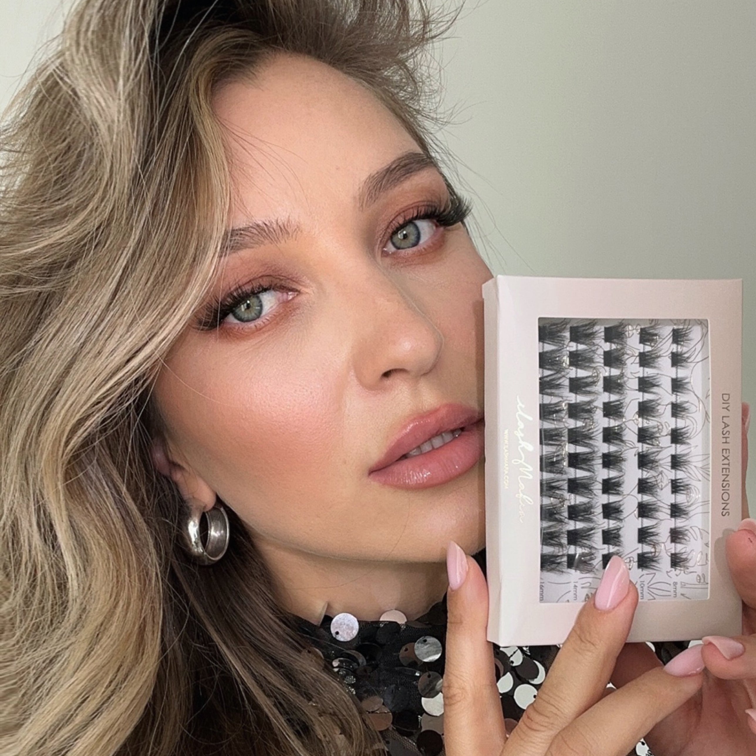 Beauty model showcasing iLash Mafia Bestie at-home lash extensions while holding a tray of reusable lash segments. The lightweight DIY lashes create fluffy definition, customizable lash mapping, and a salon-inspired lash look designed for self-application.