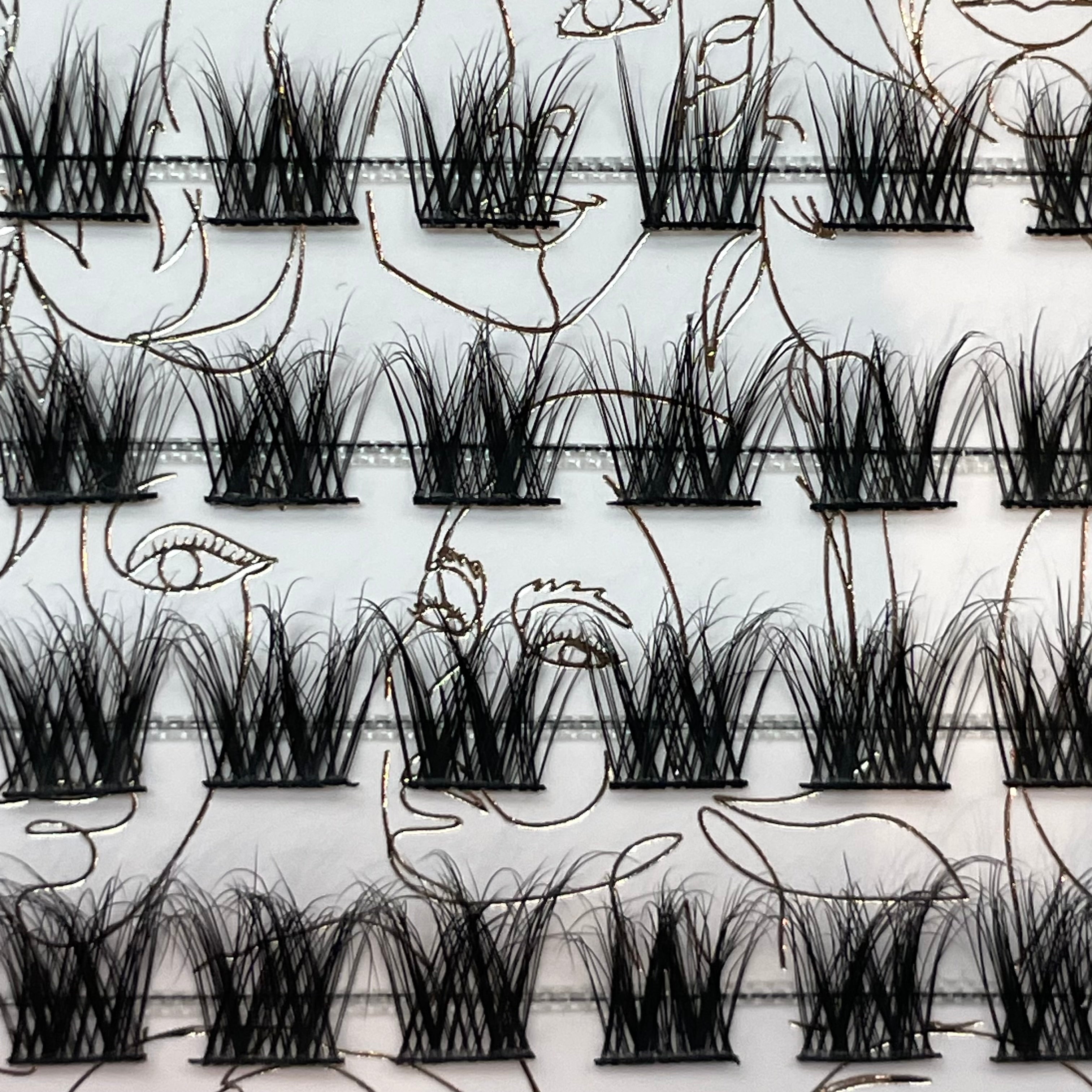 Close-up of iLash Mafia Bestie reusable lash segments arranged on a tray for custom lash mapping. The lightweight DIY lash system features soft volume clusters that can be combined to create natural lashes, wispy lash styles, doll eye looks, cat eye effects, and personalized at-home lash extension designs.