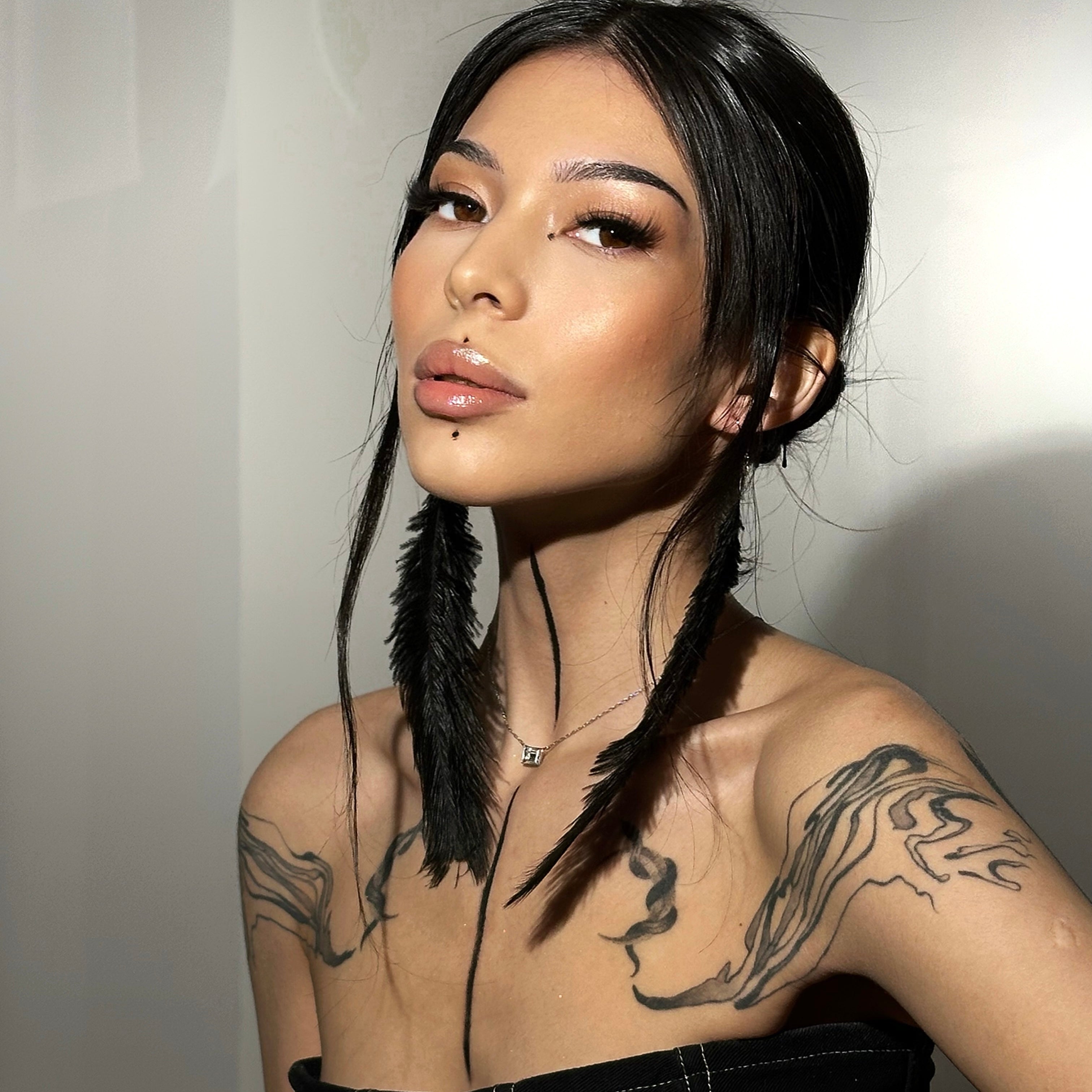 Model wearing iLash Mafia Main Character DIY lash extensions featuring dramatic volume, bold texture, fluffy density, and a glamorous eye-opening effect. Styled with dark hair, feather earrings, and artistic tattoos to showcase the edgy full-glam lash look